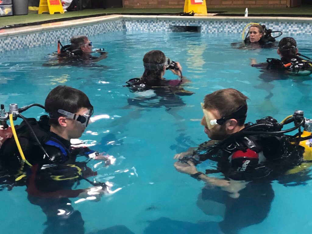 Group of children learning scuba diving in a pool as part of their enrichment week