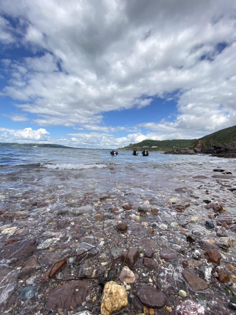 Scuba divers entering the water from the Devon shore